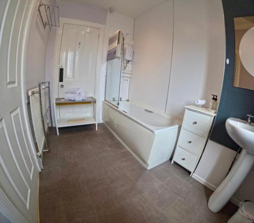 a white bathroom with a tub and a sink at Hunters Guest House in Brodick