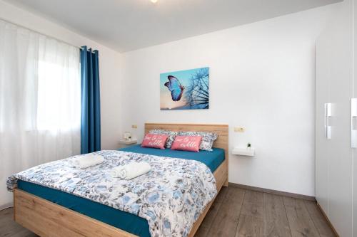 Schlafzimmer mit einem Bett mit einer blauen und weißen Bettdecke in der Unterkunft Apartman Jelena in Vrbnik