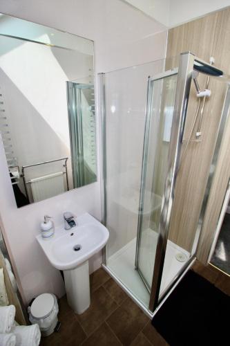 a bathroom with a white sink and a shower at Hunters Guest House in Brodick