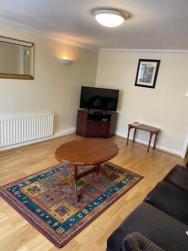 a living room with a table and a flat screen tv at Large Townhouse with Gardens in Kingscourt