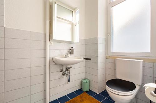 a bathroom with a toilet and a sink and a window at MUE Cubes in Basel