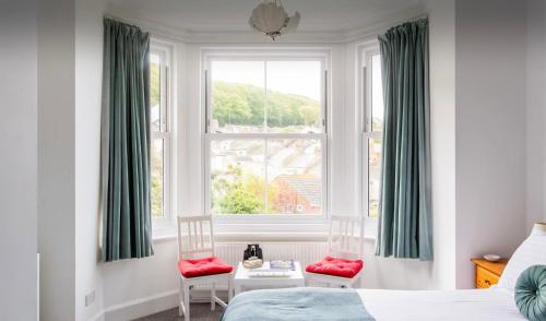 a bedroom with a bed and two chairs and a window at Brackenbury House in Portland