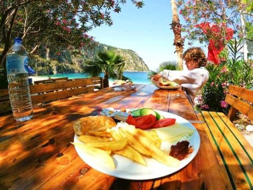 厄呂代尼茲的住宿－Butterfly Valley Beach Glamping with Food，坐在餐桌上吃一盘食物的孩子