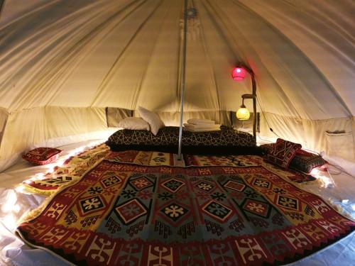 ein Bett in einem Zelt mit einer Decke darauf in der Unterkunft Butterfly Valley Beach Glamping with Food in Oludeniz