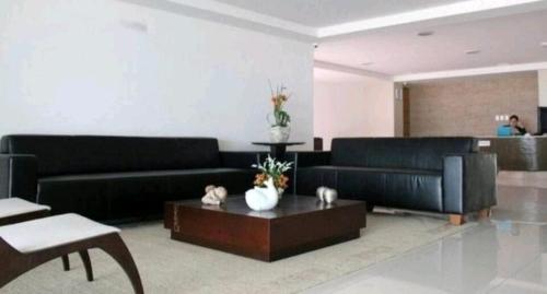 a living room with black couches and a coffee table at Studio completo na praia de Manaíra, apt 213 in João Pessoa