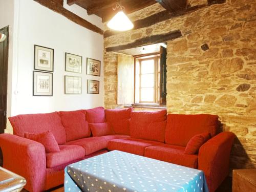 Sofá rojo en una habitación con pared de piedra en Corredoira, en Vivero
