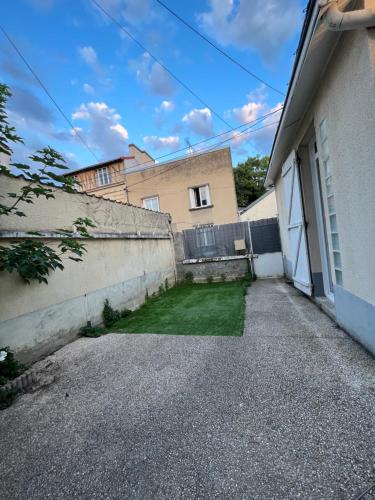 a building with a yard next to a wall at Charmante Mancelle 24h hyper centre in Le Mans