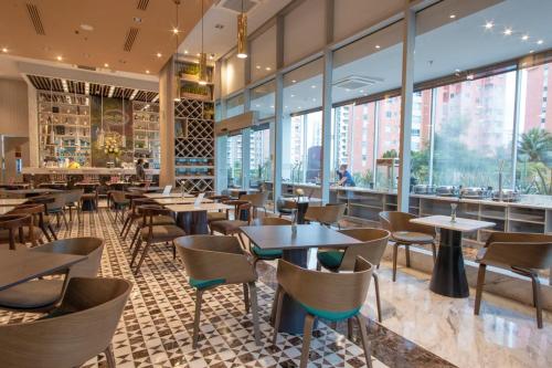 a restaurant with tables and chairs and large windows at Crowne Plaza Barranquilla by IHG in Barranquilla