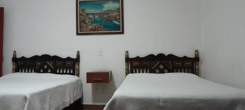 um quarto com duas camas e uma foto na parede em Posada de San Agustin em Pátzcuaro