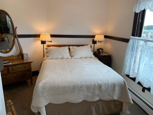 a bedroom with a white bed with two lamps and a mirror at Inn At Creek Street in Ketchikan