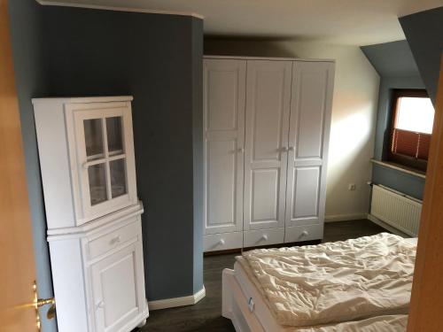 a bedroom with a bed and a white cabinet at ton Timmermanns Hus in Prerow