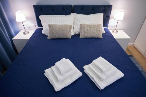 a blue bed with two white towels on it at Riverside Dziwnów Apartament i SPA in Dziwnów