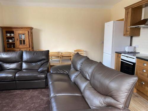 a living room with a leather couch and a refrigerator at Wagtail Cottage in Cloughton