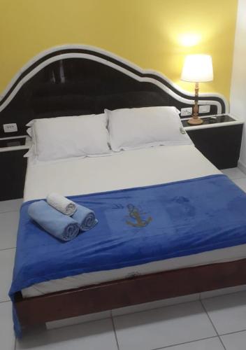 a bedroom with a large bed with a blue blanket at Ancora Peruibe Hotel in Peruíbe