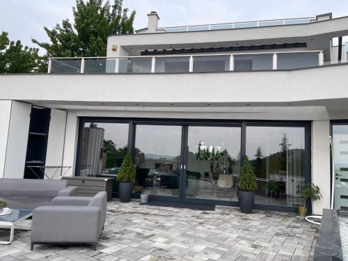 dom z dużymi oknami i patio w obiekcie Luxurious Panorama House with Pool and Sauna w mieście Budaörs