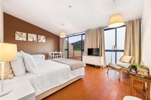 a bedroom with a large white bed and a television at Beira Rio in Mértola