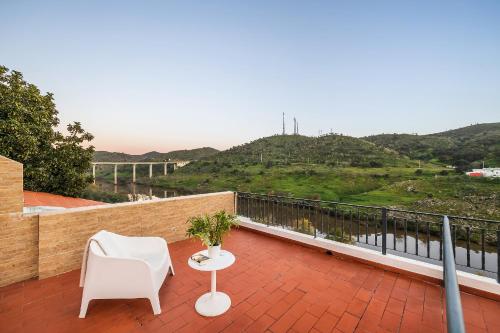 a balcony with a white chair and a table at Beira Rio in Mértola