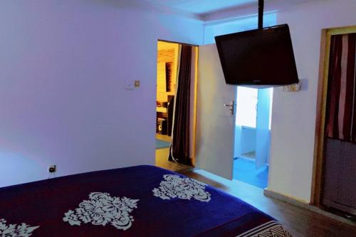 a bedroom with a bed with a blue blanket and a window at Maleeks Apartment Ikeja "Shared 2Bedroom Apt, individual private rooms and baths" in Lagos