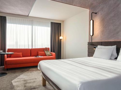 una camera d'albergo con un letto e un divano rosso di Novotel Rotterdam Brainpark a Rotterdam