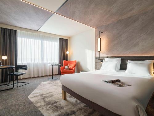 una habitación de hotel con una cama grande y una silla roja en Novotel Rotterdam Brainpark en Róterdam