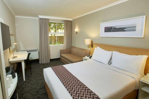 una habitación de hotel con una cama grande y una silla en StayEasy Century City en Ciudad del Cabo