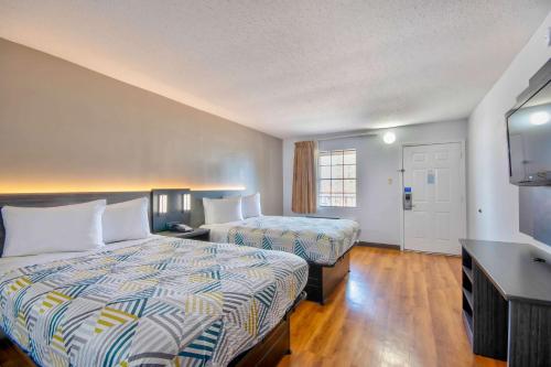 a hotel room with two beds and a flat screen tv at Motel 6 Bossier City, La in Bossier City