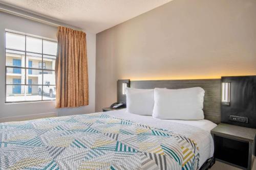 a bed in a hotel room with a large window at Motel 6 Bossier City, La in Bossier City