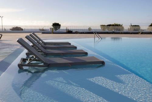 een rij ligstoelen in een zwembad bij Radisson Blu Resort, Lanzarote Adults Only in Costa Teguise