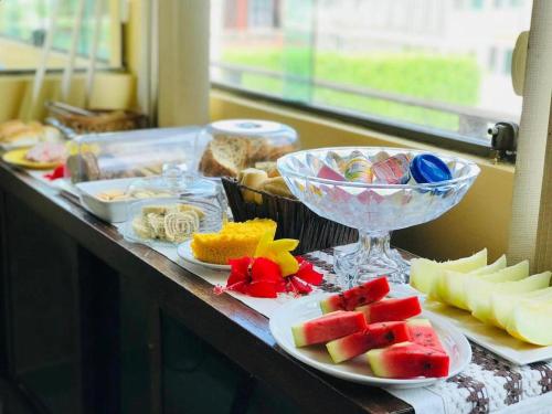 a buffet with plates of food and bowls of fruit at Pousada Luna in Fernando de Noronha