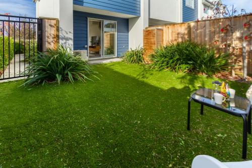 un pequeño patio con césped verde y una mesa en 2 bed Escape, Heart of Riccarton w/carpark en Christchurch