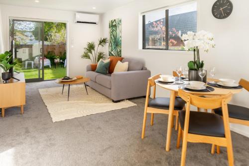 uma sala de estar com uma mesa e cadeiras e um sofá em 2 bed Escape, Heart of Riccarton w/carpark em Christchurch