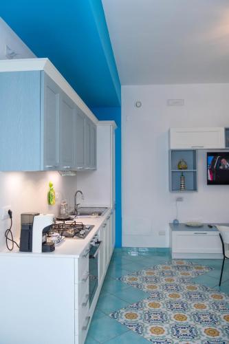 a kitchen with white cabinets and a blue ceiling at Casa Sammarco in Minori
