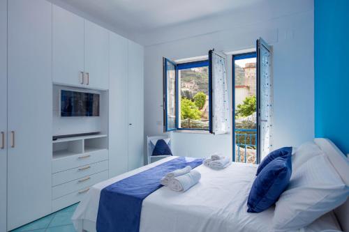 um quarto azul e branco com uma cama e janelas em Casa Sammarco em Minori