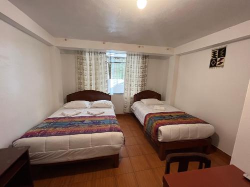 a bedroom with two beds and a table and a window at Catari's House in Machu Picchu