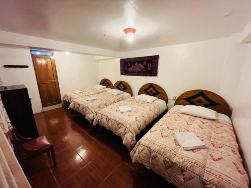 a hotel room with three beds in a room at Catari's House in Machu Picchu