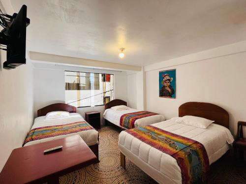 a hotel room with two beds and a table at Catari's House in Machu Picchu
