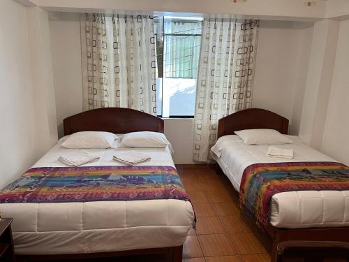two beds in a room with two windows at Catari's House in Machu Picchu