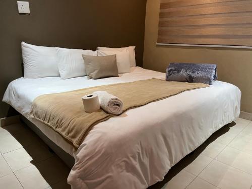 a large bed with two towels on top of it at Maponya Guest House in Pimville