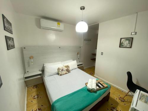 a small bedroom with a bed with a green blanket at Hotel Nogales Riohacha in Ríohacha