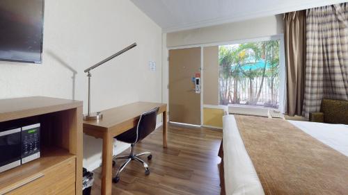 a hotel room with a bed and a desk with a computer at Rodeway Inn & Suites Fort Lauderdale Airport & Cruise Port in Fort Lauderdale