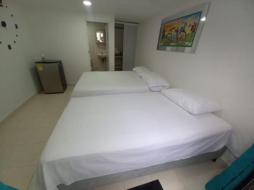 1 dormitorio con 2 camas con sábanas blancas en Hostal Doña Betty, en Cartagena de Indias
