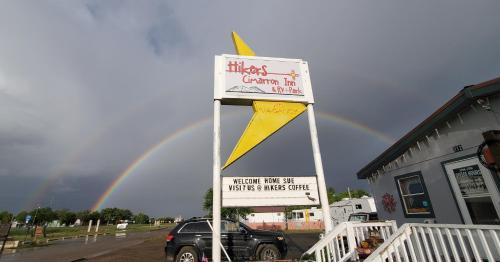 a sign in front of a building with a rainbow in the sky at Hikers Cimarron Inn & RV Park in Cimarron