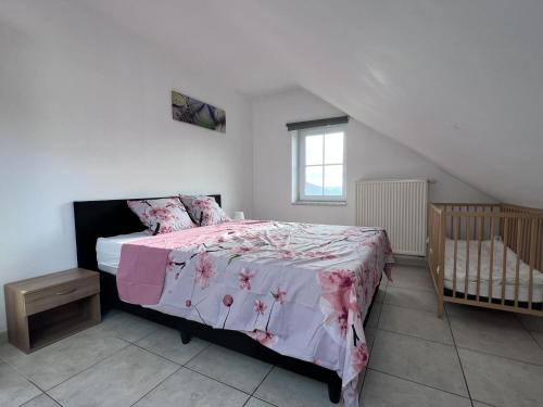 a bedroom with a bed with a pink blanket and a crib at Bra de Pierre in Lierneux