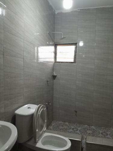 a bathroom with a toilet and a sink at Jiso Family Apartment in Tamale