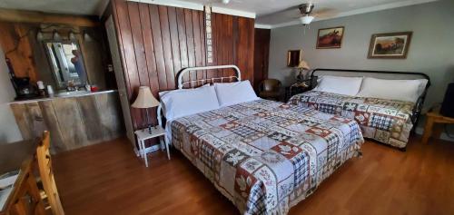 a bedroom with two beds and a wooden floor at Hikers Cimarron Inn & RV Park in Cimarron