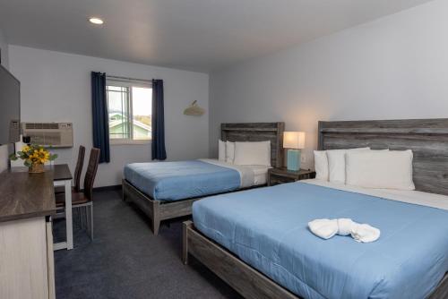 a hotel room with two beds and a desk and a kitchen at RiverWalk Inn in Pagosa Springs