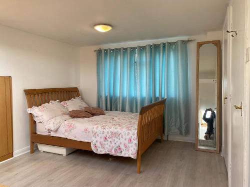 a bedroom with a bed with blue curtains and a mirror at Comfortable Room in Upper Norwood