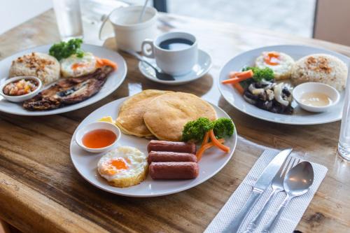 a wooden table with plates of breakfast food on it at Microtel by Wyndham Tarlac in Tarlac