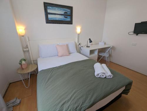 een slaapkamer met een bed met twee handdoeken erop bij Studio 18 Wright Lodge in Adelaide