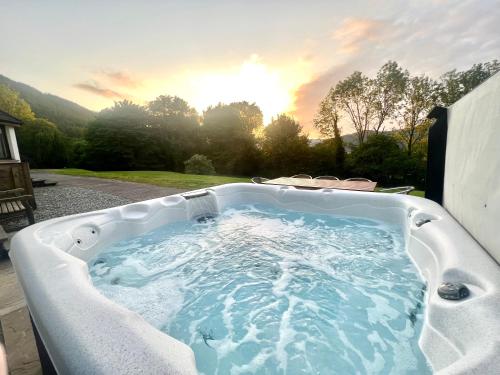 a jacuzzi tub with the sunset in the background at Wildwood Cottage with Hot Tub in Glencoe